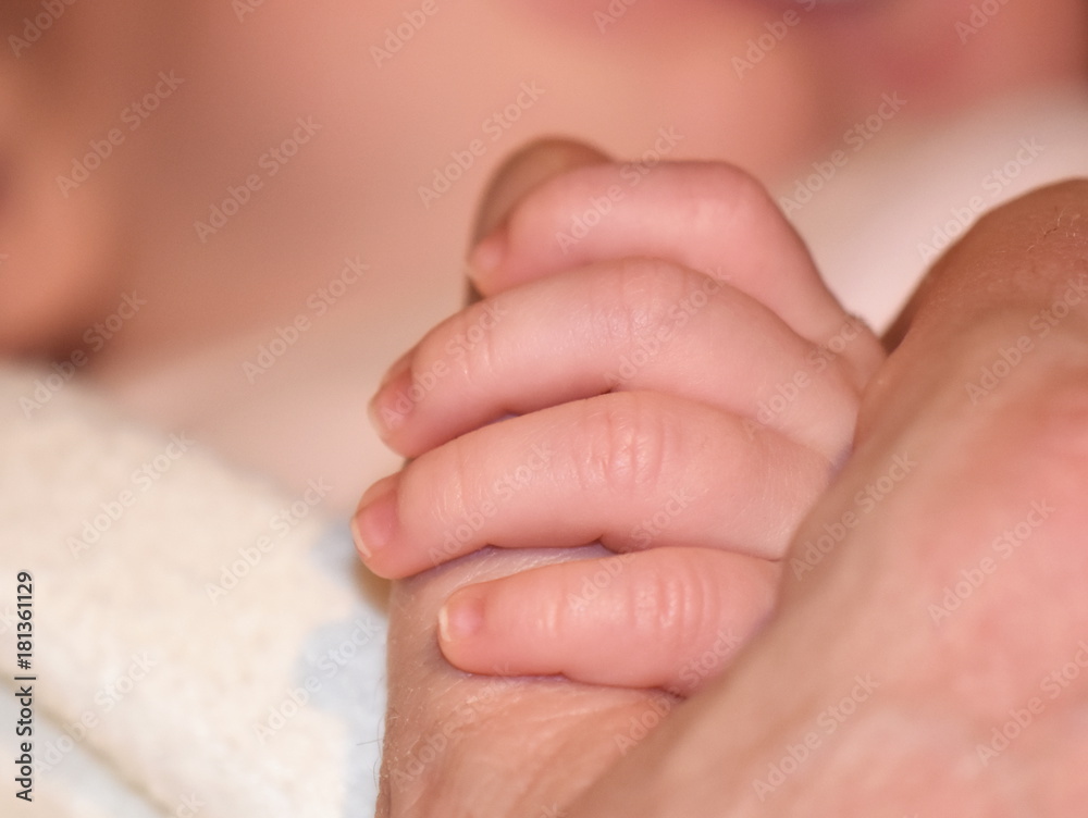 Baby holding a tight grip around a mans thumb Baby holding a tight grip around a mans thumb