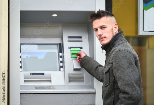 young man insert credit cart to atm