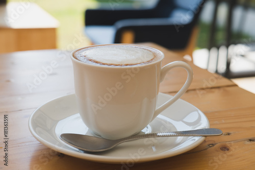 Cup of cappuccino coffee, hot mocha drink with cream on wood table