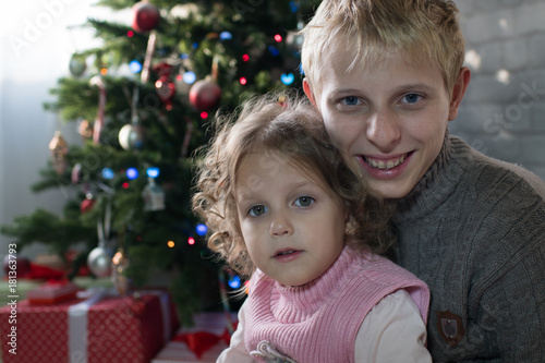 Girl and boy playing in the room with a Christmas tree