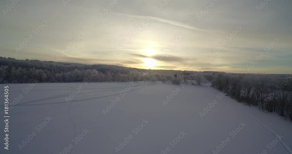 A drone shot of a open feild surounded by trees and the sun is rising is the back A drone shot of a open feild surounded by trees and the sun is rising is the back