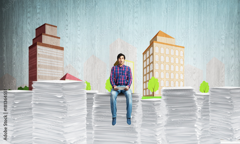 Young man sitting on pile of paper documents. Young man sitting on pile of paper documents.