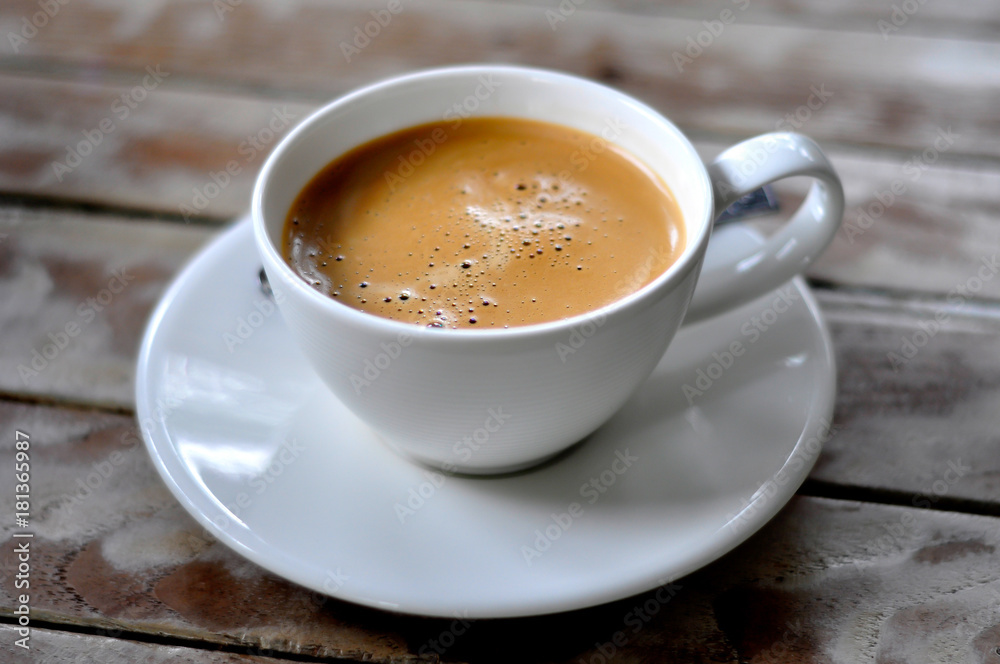 Coffee in a white cup placed on a wooden table Coffee in a white cup placed on a wooden table