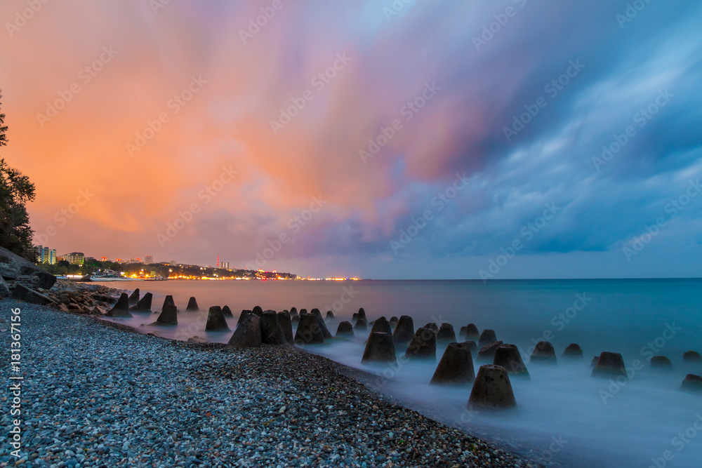 Long exposure photo of the concrete conical boulders lying in the sea on the background of coastline of Sochi at dawn, Russia
