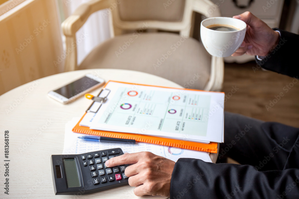 Fototapeta premium Man using calculator and writing make note with calculate and drink coffee at work