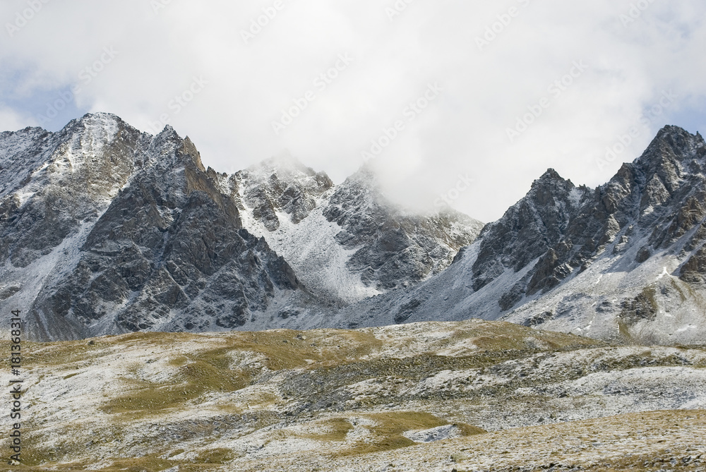 Landscape: mountains covered with fresh snow (Castel, Kastelhorn peak), after a snowstorm, yellow and green grass, autumn, clouds, shadows, rsun ays, wind, rock, Fromazza, Piedmont, freedom, Italy
