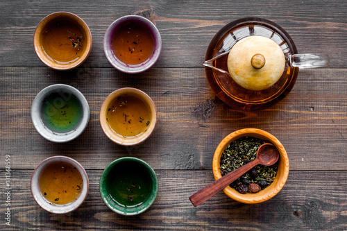 Accessories for tea ceremony. Tea pot, cups, dry tea leaves on dark wooden background top view