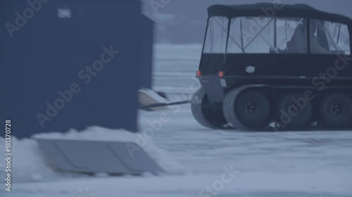 A person is bringing his ice hut to a different part of the lake 