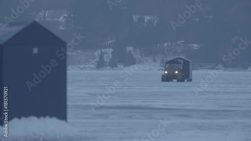 A veichcle is bringing a hut across the ice to fish in