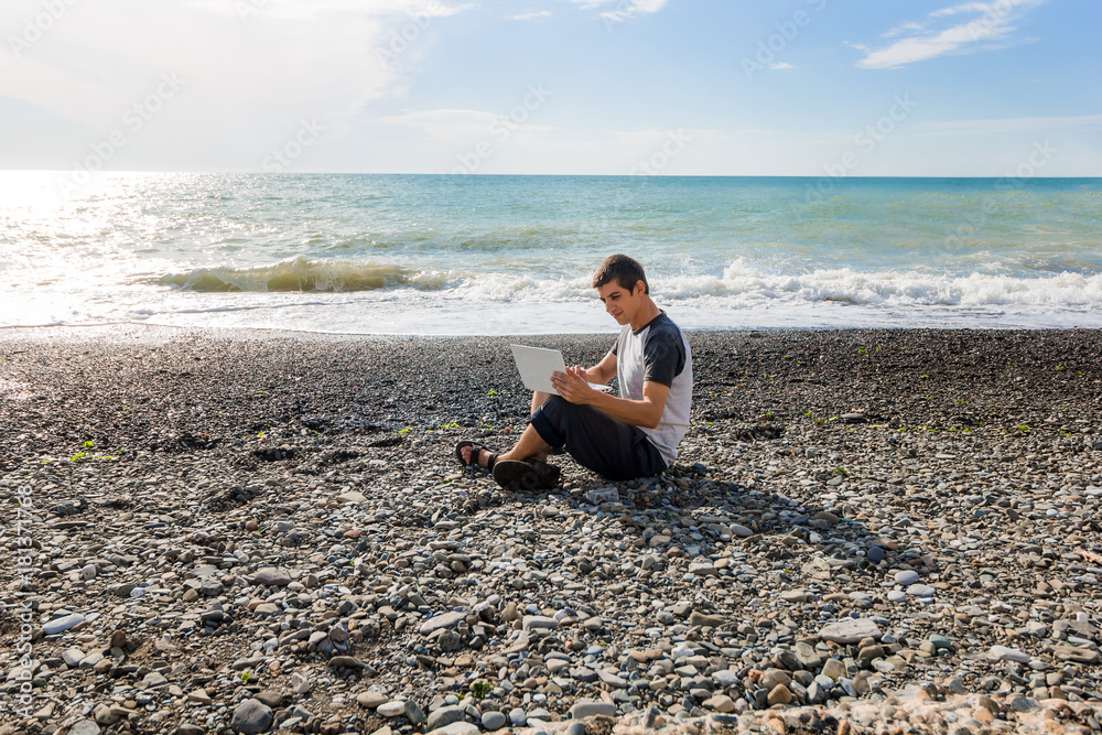 young man freelancer working with a laptop on the beach