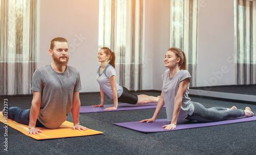 two beautiful girls and man do yoga in the sport center and spa. The concept of a healthy lifestyle.