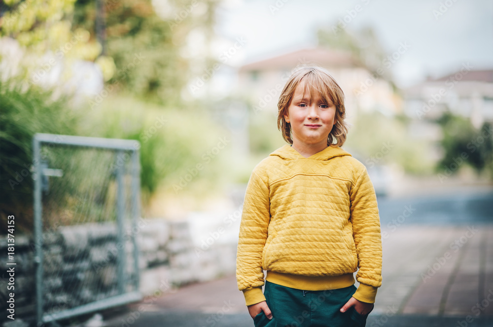 Outdoor fashion portrait of cute little boy wearing yellow hoody sweatshirt