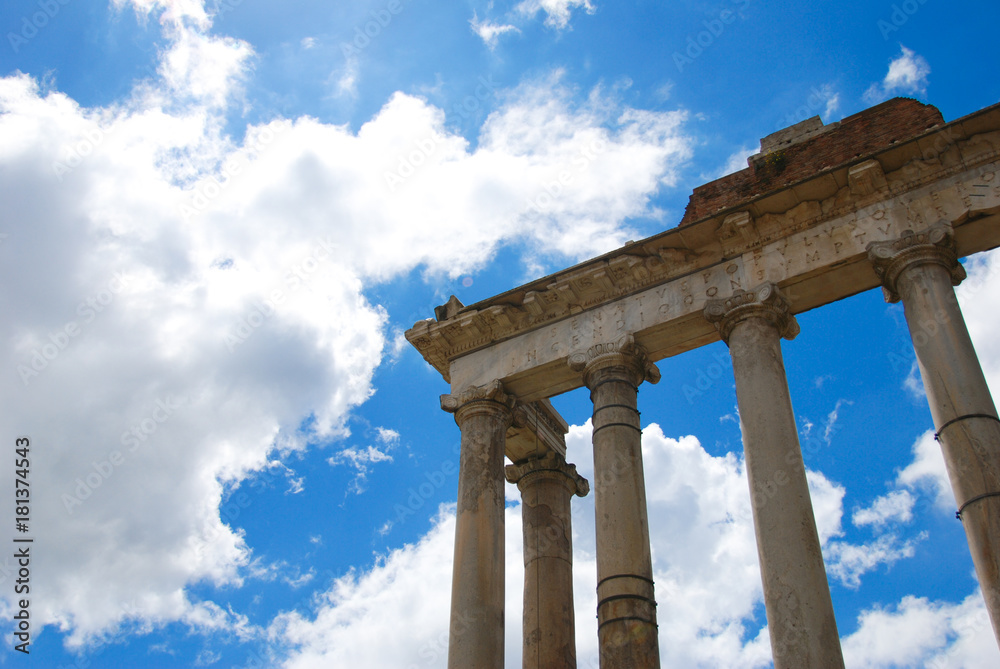 Rome. The Temple of Saturn in the Roman Forum. In the background blue sky and clouds.