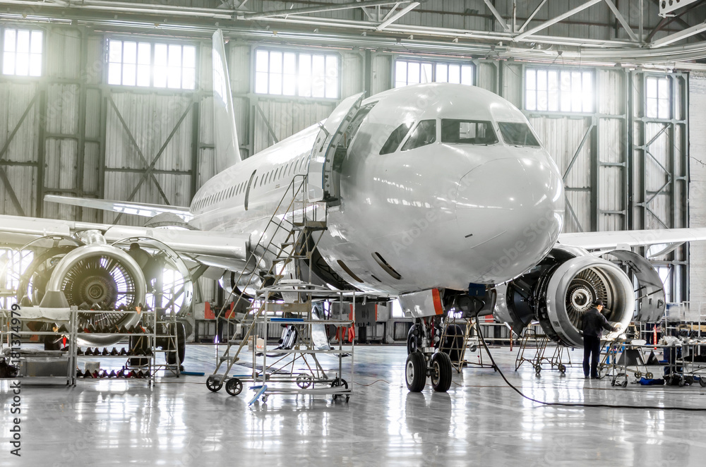Obraz premium Samoloty pasażerskie w zakresie konserwacji silnika i kadłuba w hangarze lotniskowym.