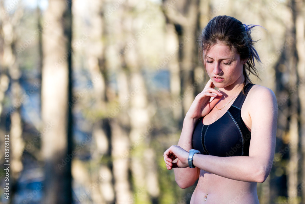 Sporty woman monitors heart rate while running in forest. Sporty woman monitors heart rate while running in forest.