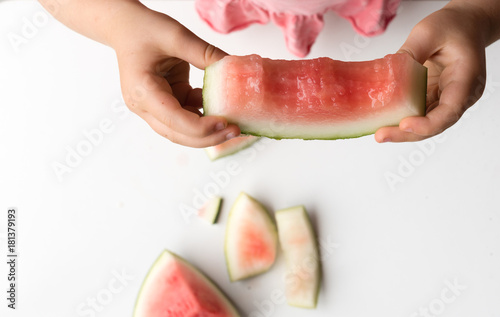 HIgh angle cropped view of little girl holding half eaten watermelon slice (selective focus)