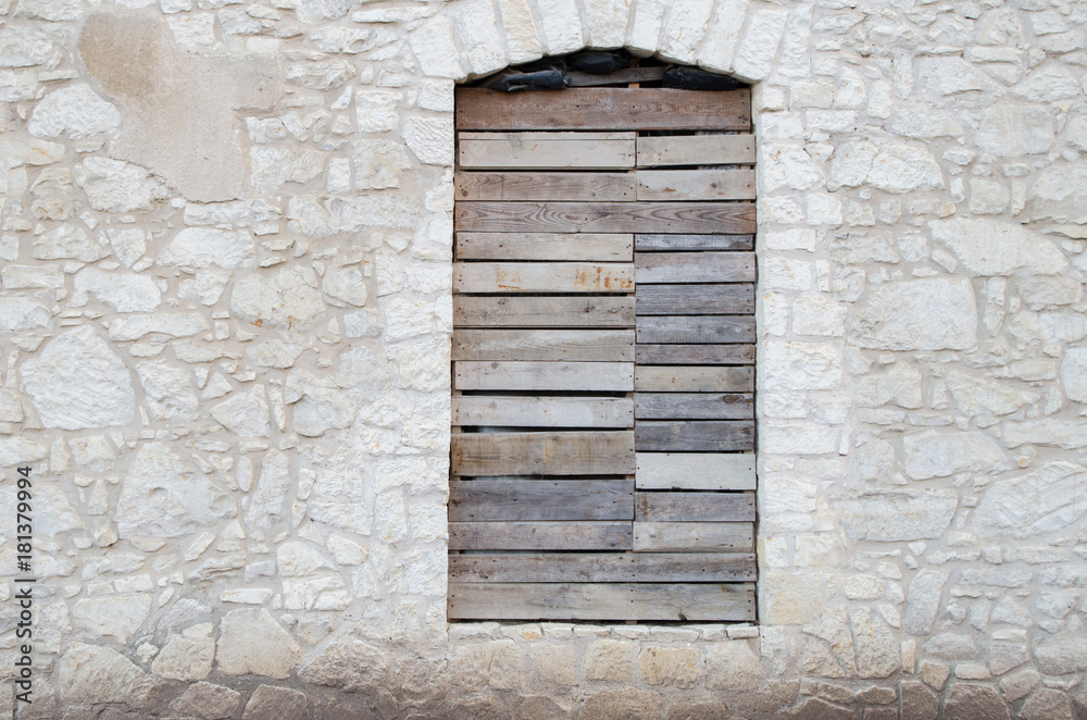 Facade of an abandoned old stone limestone house with boarded up window, copy space Facade of an abandoned old stone limestone house with boarded up window, copy space