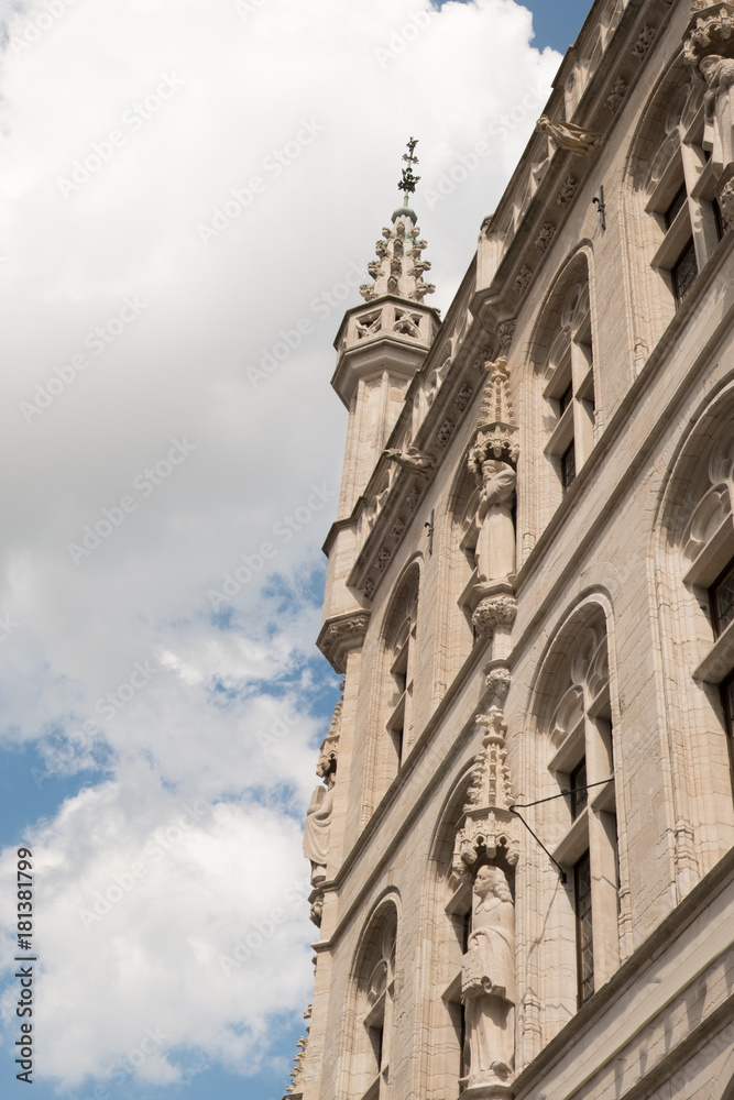Exterior of a Gothic building in Leuven Belgium.  Crockets adorn the pinnacles topped with a lion finial. Carved statues on the exterior of historic Gothic building in Belgium.