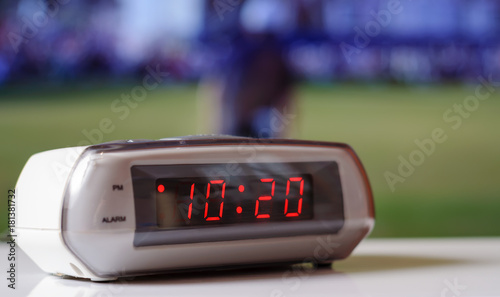 White electronic clock with a red dial. White clock with an alarm clock