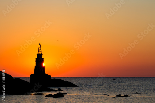 Sun peeks behind Ahtopol lighthouse in Black Sea in Bulgaria