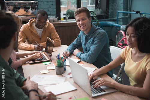 Portrait of outgoing group of people having job locating at table. Girls typing on laptops. Business concept