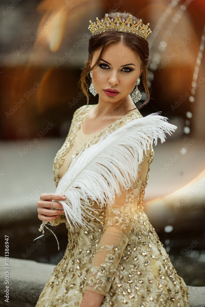 Beautiful sexy woman with fashion makeup is wearing princess dress and  crown holding white feather Stock Photo | Adobe Stock