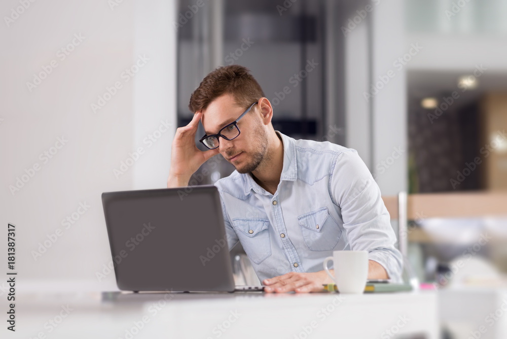 Pensive businessman reading something from laptop at office. Pensive businessman reading something from laptop at office.