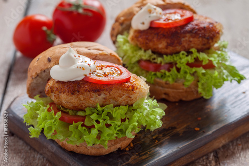 chicken burgers with vegetables on a wooden table