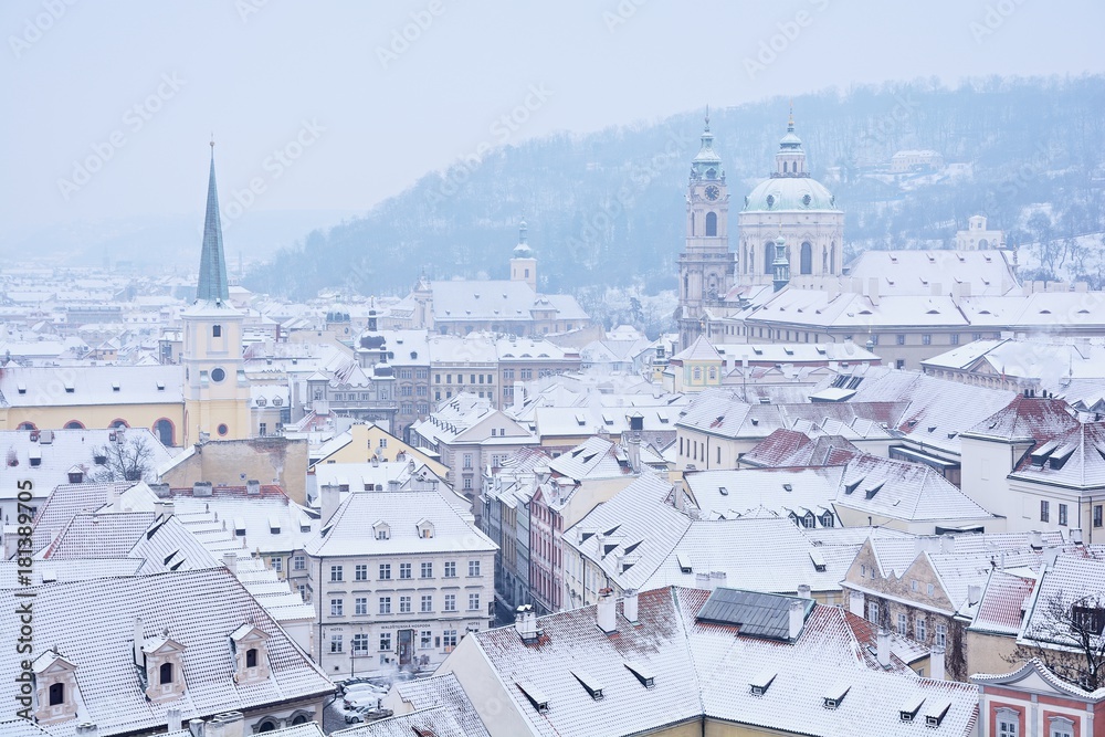 Fototapeta premium Winter Prague panorama with St. Nicholas church, roofs of Lesser Town and Petrin Hill