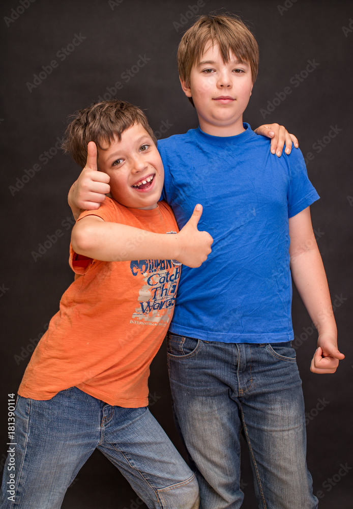 Brothers having fun whilst posing. Boys portrait, young little cute and adorable kids, little obstreperous scamps. Poses, face expressions, ease,  black background. - obrazy, fototapety, plakaty 