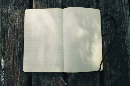 Blank empty moleskine notepad see from top on wooden table in a park photo
