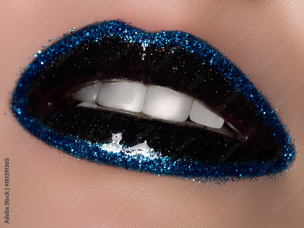 Naklejka premium Macro shot of an open mouth with decorative fashionable cosmetics. Black lipstick and spangles on lips. Fashion, beauty, cosmetology and make-up