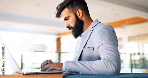 Professional handsome businessman using laptop at workplace