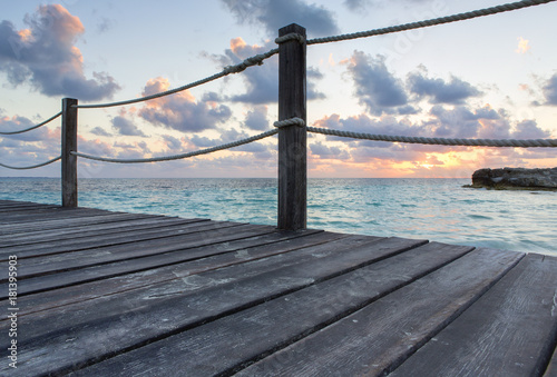 Fototapeta Naklejka Na Ścianę i Meble -  Beautiful sunrise on the Caribbean ocean. Image taken on a long wooden pier. Cloudy sky, colourful sunrise. Silent and peaceful morning.