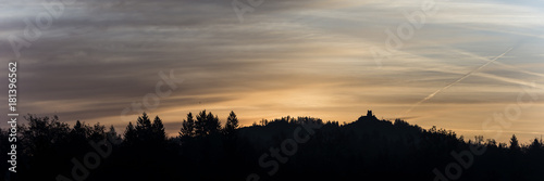 Old building on a forested mountain silhouetted against the fiery glow of the rising sun © Gajus