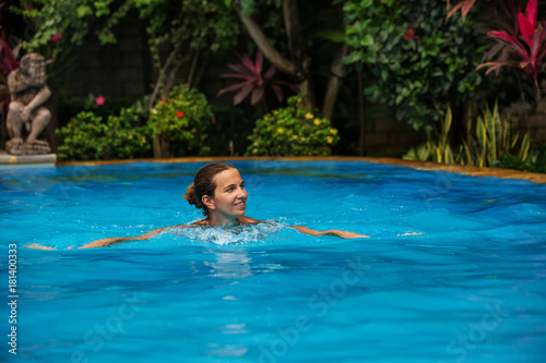 Caucasican woman rests in blue pool in tropics