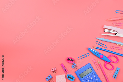 Stationary concept, Flat Lay top view Photo of Scissors, pencils, paper clips,calculator,sticky note,stapler and notepad in pink and blue tone on pink background with copy space