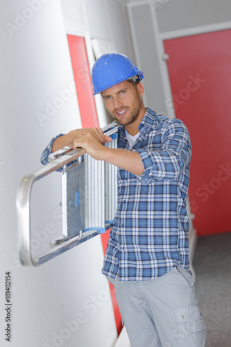 smiling worker holding a ladder
