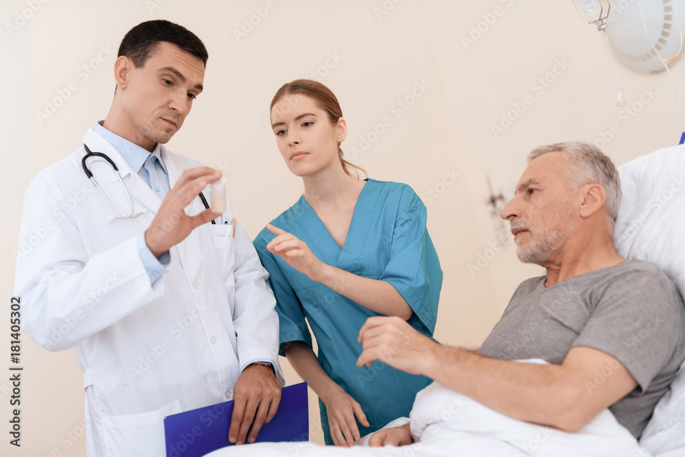 The old man lies on a cot in the medical ward, and next to him there is a doctor and a nurse. The old man lies on a cot in the medical ward, and next to him there is a doctor and a nurse.