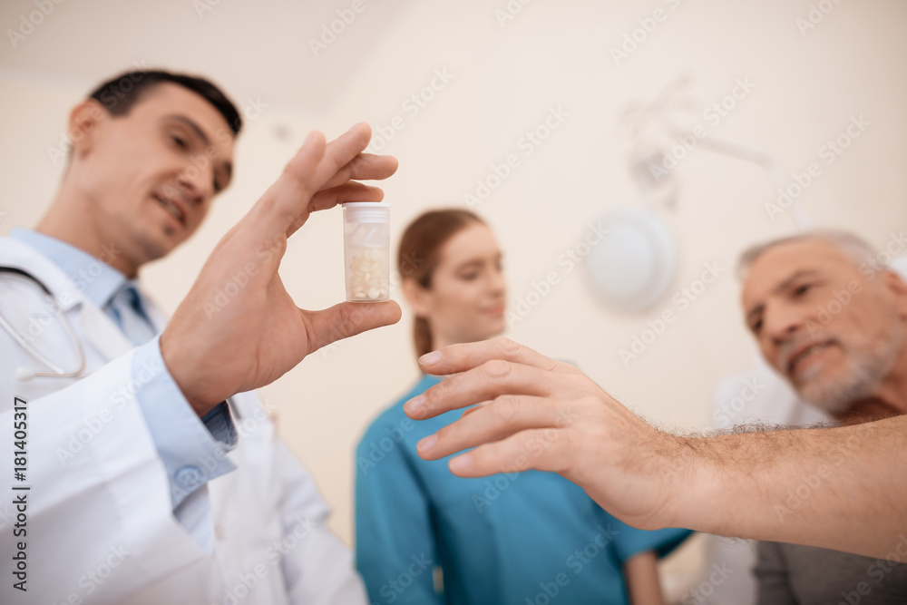 Obraz premium The old man lies on a cot in the medical ward, and next to him there is a doctor and a nurse.