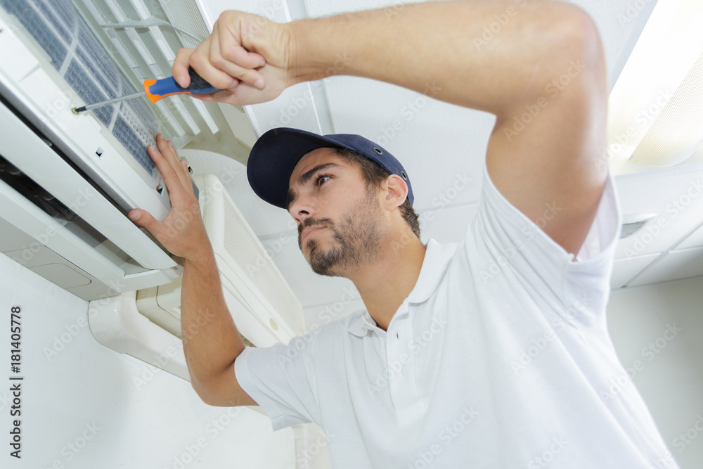 portrait of mid-adult male technician repairing air conditioner portrait of mid-adult male technician repairing air conditioner
