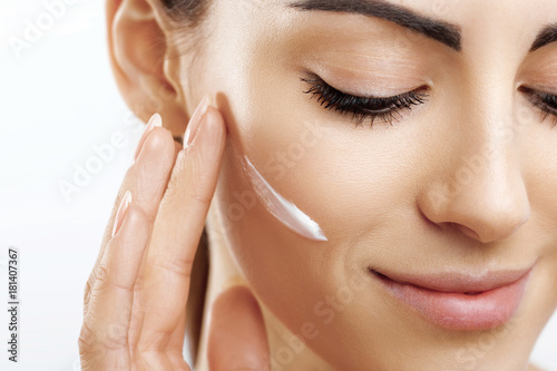 Closeup happy young woman applying cream to her face Skincare and cosmetics concept. Cosmetics. Woman face skin care.Natural makeup, touching face.