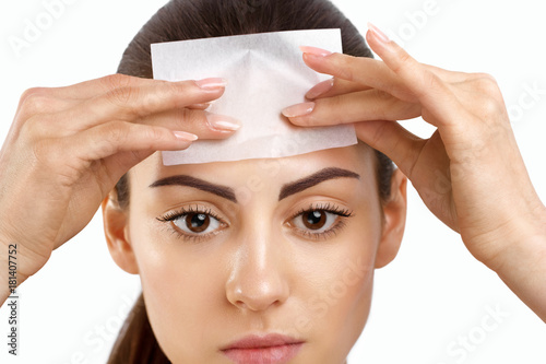 Skin Care. Woman removing oil from face using blotting papers. Closeup Portrait Of Beautiful Healthy Girl With Nude Makeup. Perfect Soft Skin With Oil Absorbing Tissue Sheets. Beauty Concept