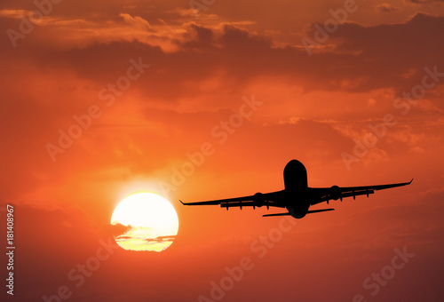 Silhouette of the aircraft and red sky with sun. Landscape with passenger airplane is flying in the sky with clouds at sunset. Travel background. Passenger airliner. Commercial airplane. Business