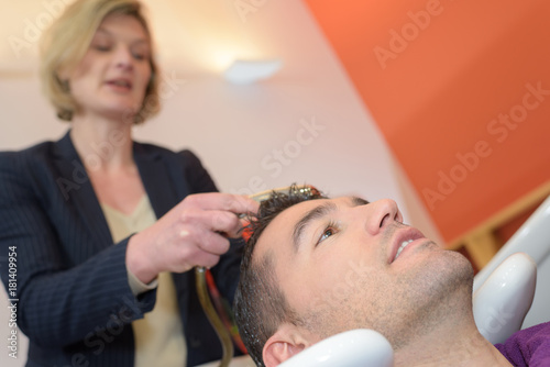 female worker washing man head in stylish barbershop