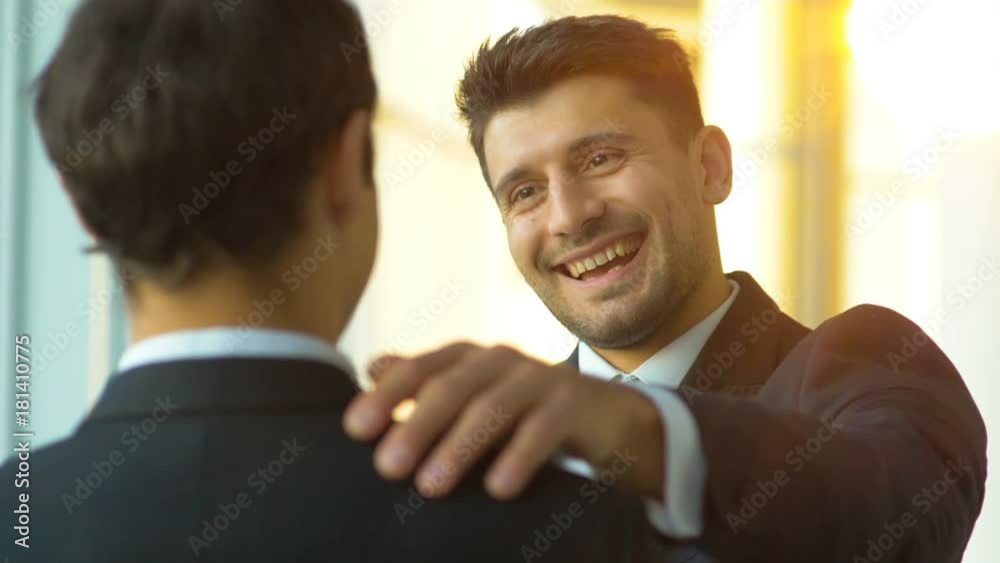 The businessmen pat on the shoulder on a sunny background. slow motion The businessmen pat on the shoulder on a sunny background. slow motion