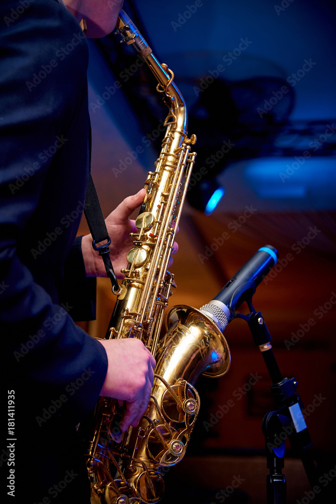 Obraz premium Saxophone in the hands of a musician near the microphone