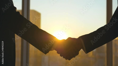 The two business people handshake on the sunset background. slow motion