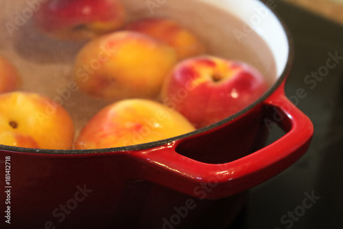 фотографія Closeup of a red pot handle while blanching peaches