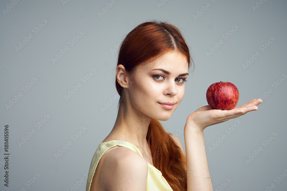 Young beautiful woman on a gray background holds an apple, fruit, diet Young beautiful woman on a gray background holds an apple, fruit, diet